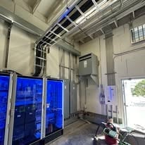 Industrial warehouse interior with blue-illuminated storage units and overhead equipment
