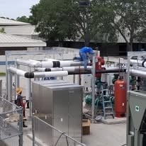 Outdoor industrial equipment and machinery yard with workers servicing rooftop units